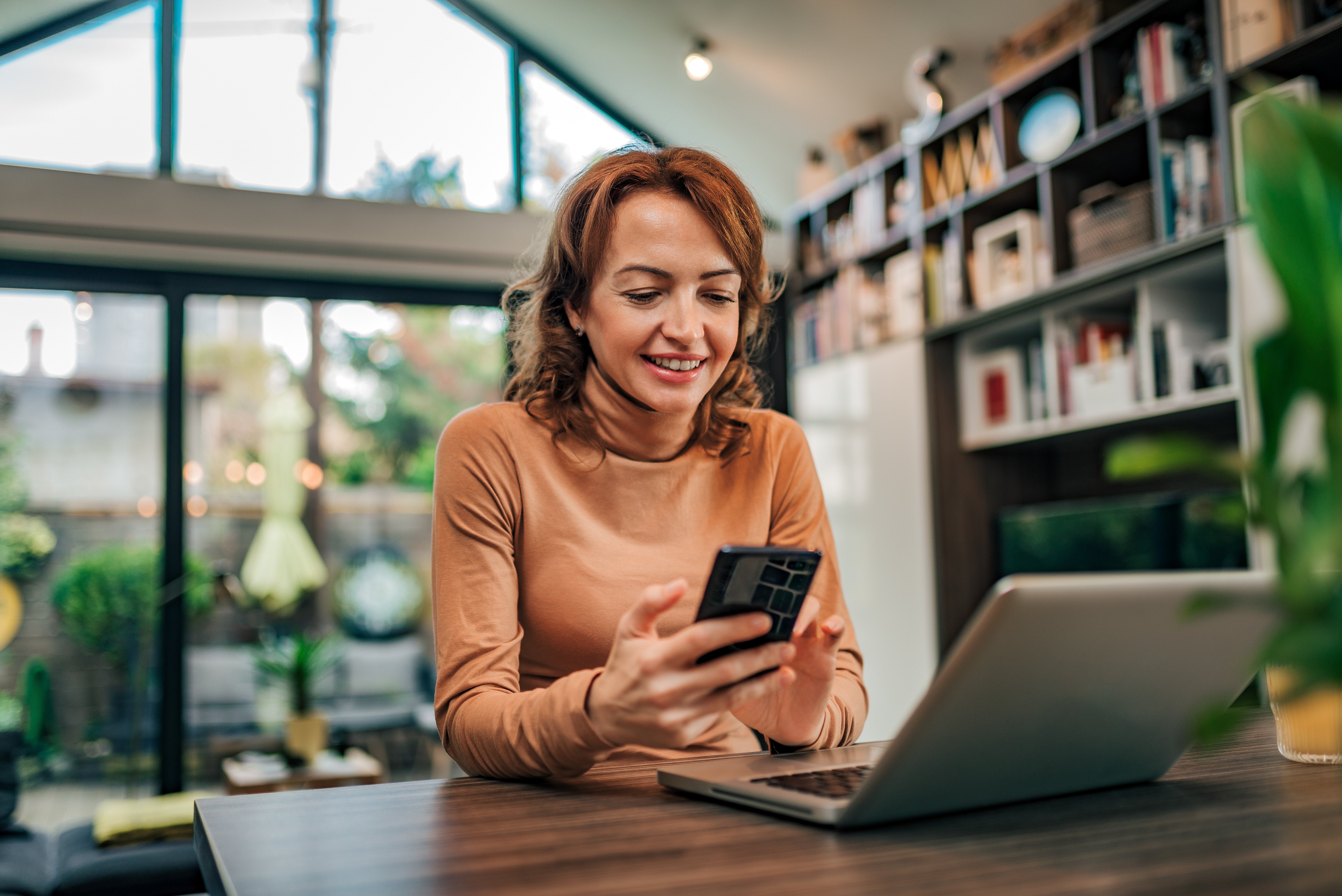 A woman sitting with on her desk with phone in hand excited