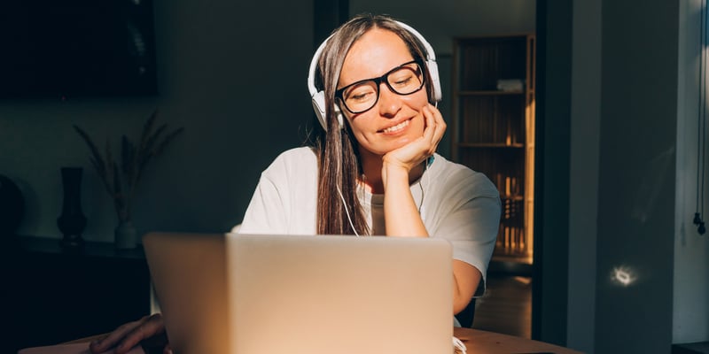 Woman smiling while working on a laptop at a desk