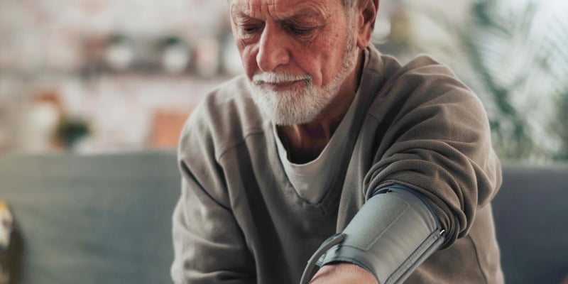 a man sitting down with a blood pressure monitor in his hand