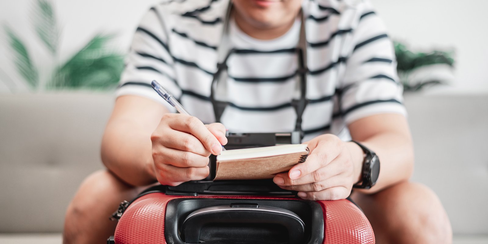 A person sitting with their luggage and checklist at hand